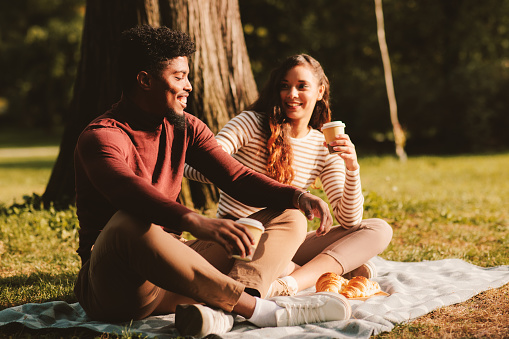 Young couple enjoying a park on a sunny day and drinking coffee