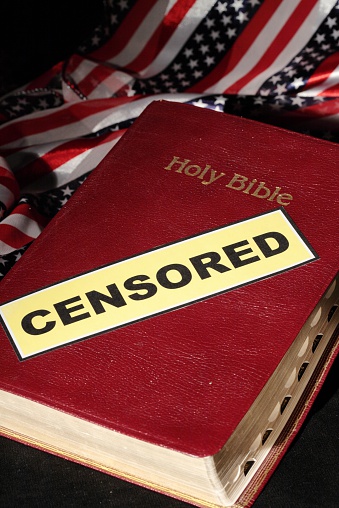 Bible with censored label laying on scarf with stars and stripes.