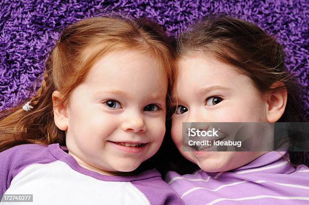 Foto de Duas Irmãs Feliz Deitado No Tapete Roxo e mais fotos de stock de 2-3 Anos - 2-3 Anos, 4-5 Anos, Alegria