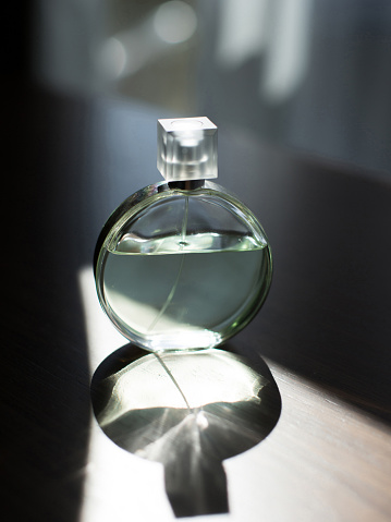 Perfume bottle on a wooden table with shadow on the floor