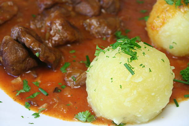 closeup of Potato Dumplings, stuffed with crouton, goulash in background
