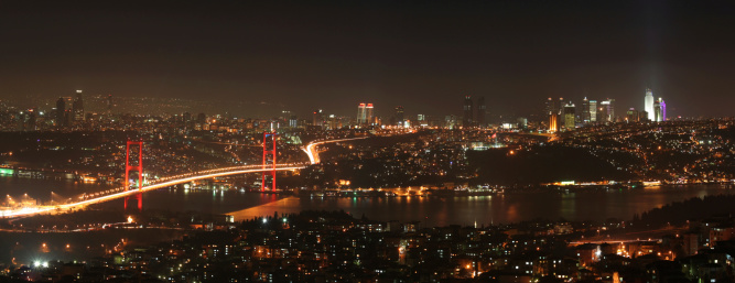 Night view of the Bosphorus Bridge and skyscrapers in Istanbul / Turkey.One side of Istanbul is in Europe and the other side is in Asia.This picture was taken from Asia side.