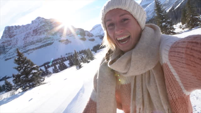 SLOW MOTION: Young woman taking selfie in snow winter landscape