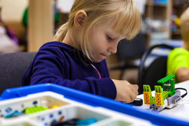 istock Child girl 5 year old inventing robot in programming classroom, construct robotic toys. Kid using constructor blocks and PC, technology homework. Learning robotics basics concept. Copy ad text space 1727425135