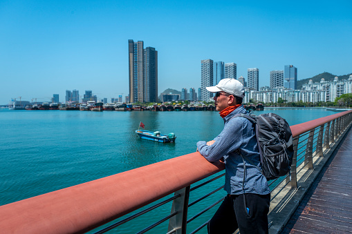 Chinese man looking at Shenzhen Bay on the walking path, Shenzhen Bay Park, Guangdong, China.