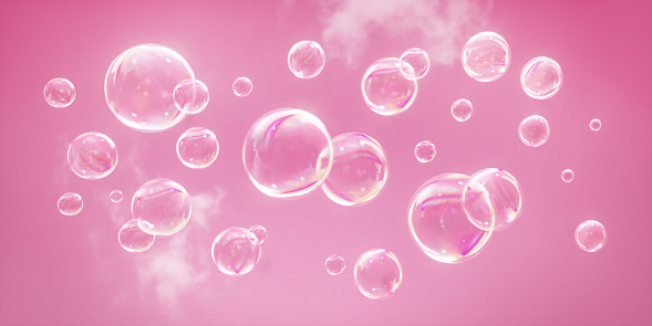 Group of colorful soap bubbles flying on a pink sky background
