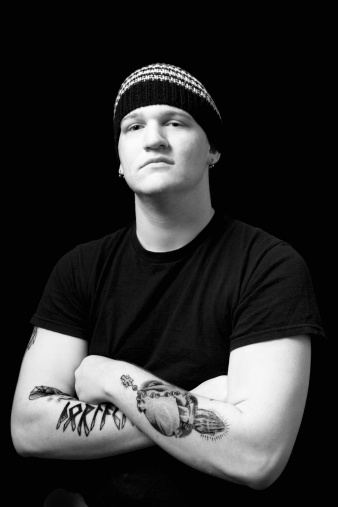 A young man looking tough with tattoos on a black background