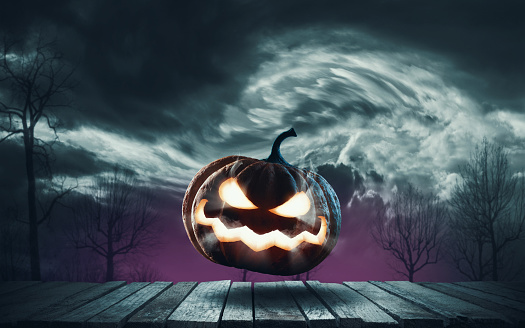 Funny Halloween pumpkin jumping on a wooden deck at night