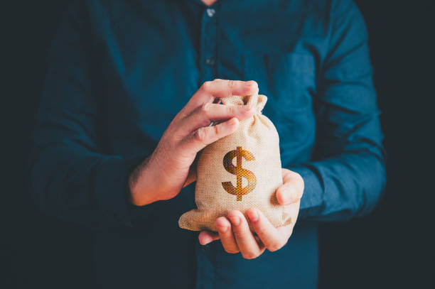 Businessman holding money bag with two hands and dollar sign background. Business and investment concept. stock photo