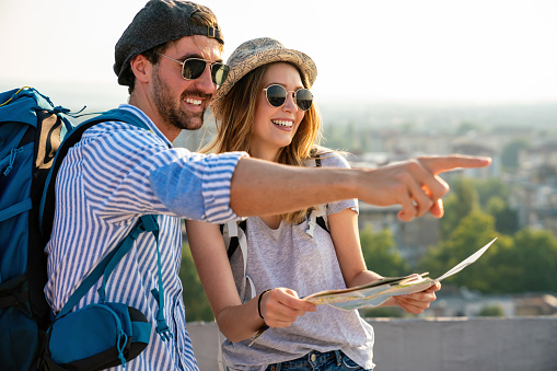 Happy tourists couple, friends sightseeing city with map together. Travel people fun concept.