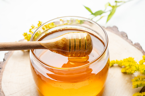 Jar with liquid flower honey, close-up, fresh honey.