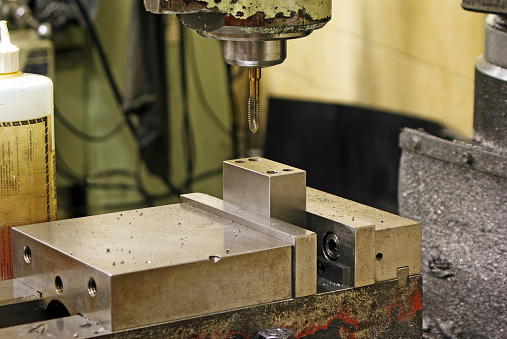The tap on a milling machine is centered over a part clamped in a vise.Similar Images: