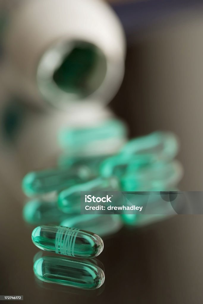 Pain killers.Advil's on reflective surface. Bottle of prescription pain killers spilt on reflective surface. Advil and Tylenol. Pharmaceutical Industry. Vertical. Acetaminophen Stock Photo