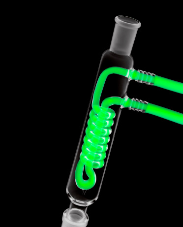 Close up of a condenser with glowing green cooling fluid. Isolated on Black.