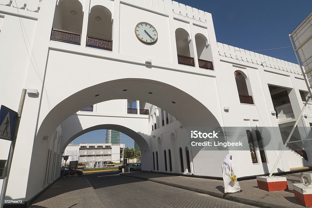 Bab Al Bahrain "Bab Al Bahrain means Gate of Bahrain and is located in Manama's central business district (CBD). Built by the British in the 1940s, Bab Al Bahrain once stood at the water's edge. Due to extensive land reclamation in the later years, one needs to walk more than 10 minutes to get to the sea. When it was originally designed by Sir Charles Belgrave in 1945, it housed the government offices of the time and overlooked the sea. The sea has long been reclaimed. Government Avenue, which runs alongside Bab Al Bahrain, and the new highway that leads to Saudi Arabia were built on reclaimed land. Currently, the Bahrain Financial Harbor is being constructed on further reclaimed land. The monument itself was refurbished in 1986 to incorporate Islamic architectural features. Today, the ground floor now houses the tourist information office and a handicrafts shop. The monument essentially consists of a huge arch, below which runs a road, which is often referred to as the entrance to the Manama souq (marketplace)." Adult Stock Photo