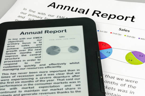 Cropped image of businessman reading business magazine on tablet and laptop in office
