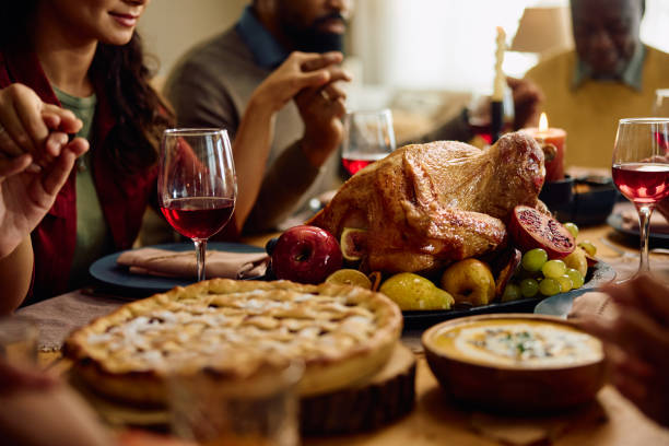 istock Thanksgiving turkey with family praying at dining table. 1727472897