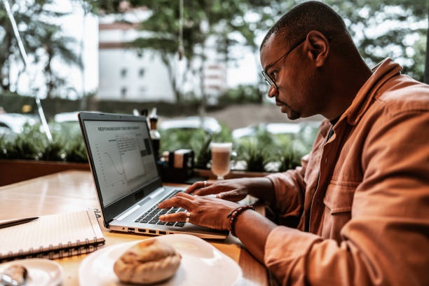 istock Mid adult man using laptop to work or study at coffee shop 1727473460