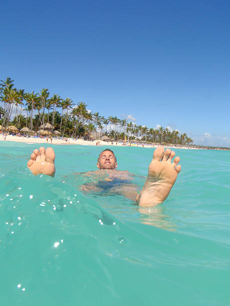 Happy man floats with his feet up on tropical blue waters
