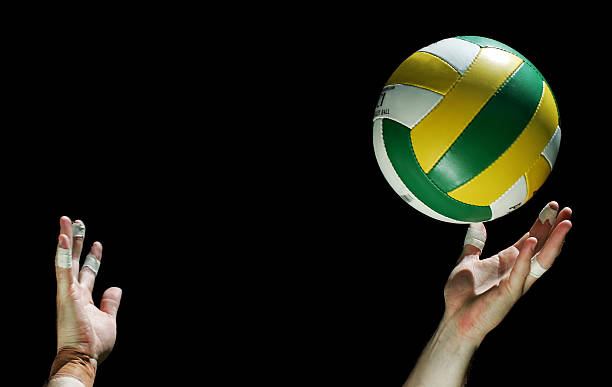 Person serving a volleyball on a black background A volleyball is thrown up about to be served in front of a black background male volleyball player stock pictures, royalty-free photos & images