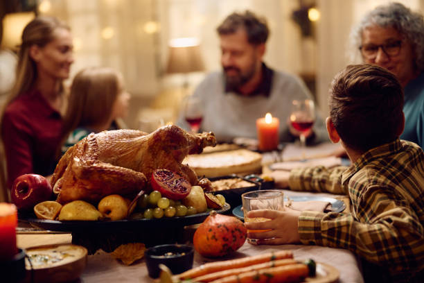 istock Thanksgiving turkey on dining table with extended family in the background. 1727479048