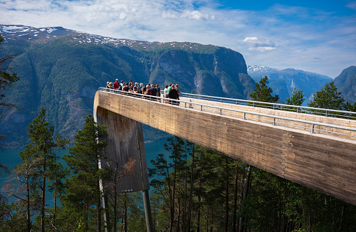 Stegastein, Norway, Jun 24, 2023: Tourists take in the views from the Stegastein Viewpoint, 650 meters above Aurlandsfjord which  is off  the mountainside by the Scenic Route Aurlandsfjellet.