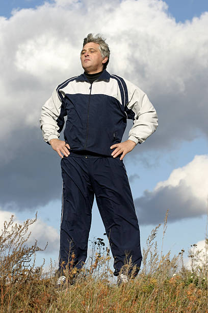 The man in a sports suit stands proudly holding a head.