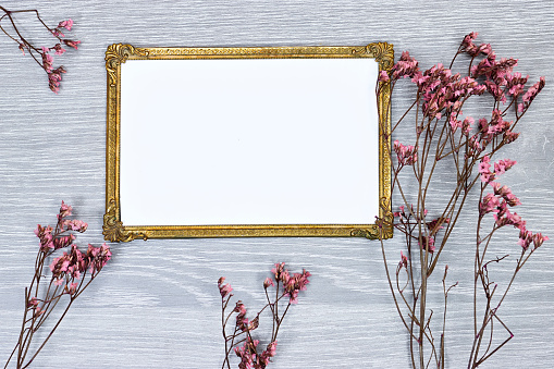 golden picture or photo frame mockup with pink baby's breath, gypsophila on gray wood table