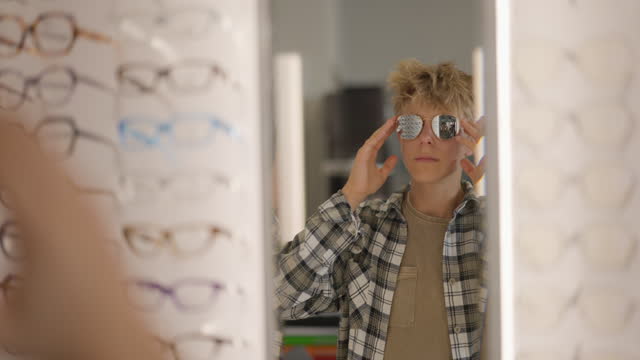 Teenage boy browsing and trying on glasses in an Optician Shop