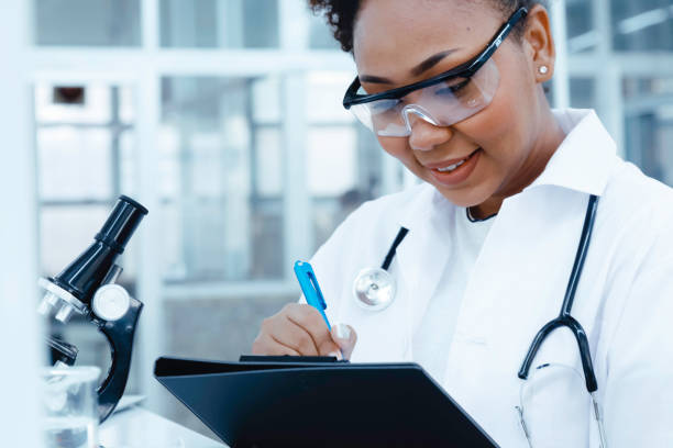 istock smiling black scientist doctor student studying and experiment analysis test sample with writing report in computer. ambitious young biotechnology Specialist. medical science laboratory education. 1727502230