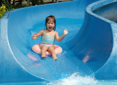 a young girl having fun sliding down on a water slide on vacation.