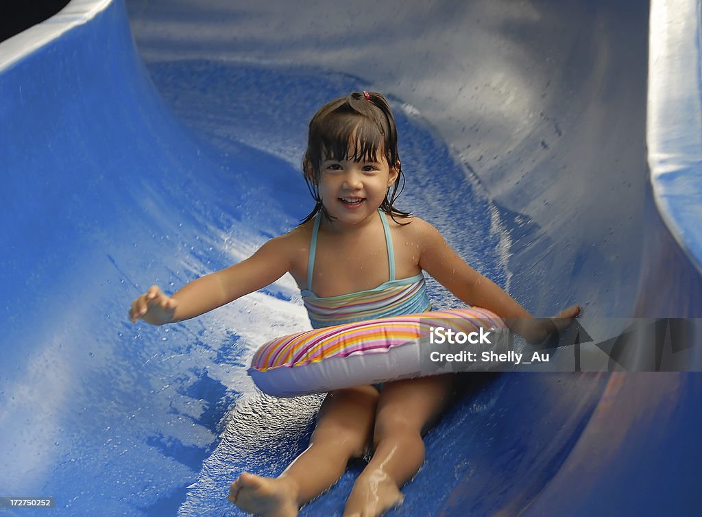 Summer Waterslide a young girl sliding down a water slide on vacation. Child Stock Photo