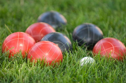 Black and red bocce balls nestled in lush green grass.