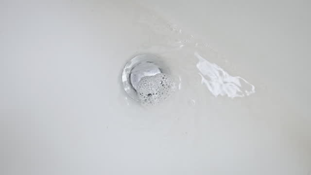 Water Drains Into the Sink in the Bathroom and Swirls in Slow Motion