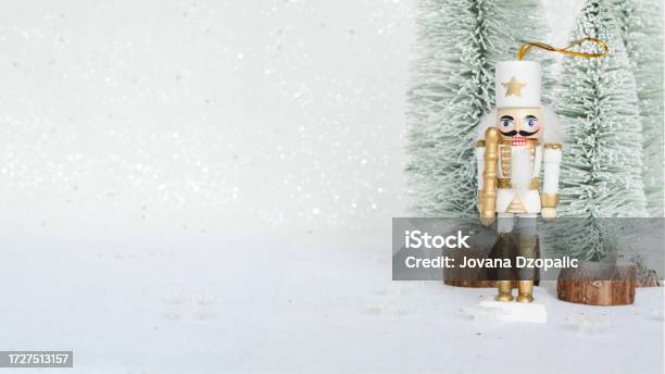 Christmas Nutcracker Toy Figurine Ornament In White Decoration For New Year Nutcracker On The White Sparkling Background With Conifers Advent Concept With Bokeh Lights Stock Photo - Download Image Now