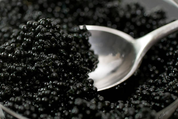 Spoon in Caviar spoon in a bowl of caviar; close up caviar stock pictures, royalty-free photos & images