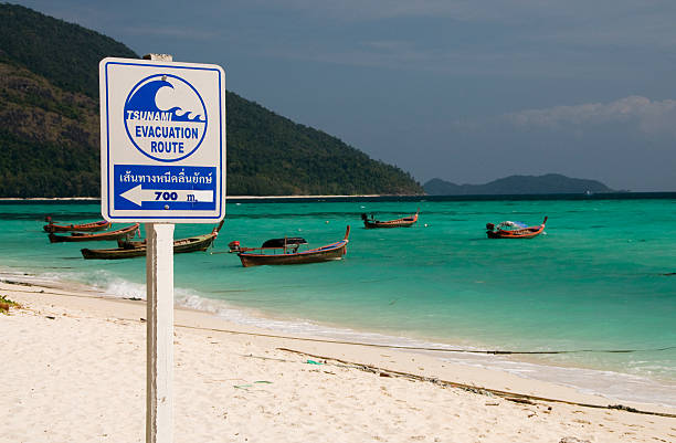 Tsunami Evacuation Sign Sign showing evacuation instructions at the beach on Koh Lipe, Thailand. 2004 indian ocean earthquake and tsunami stock pictures, royalty-free photos & images