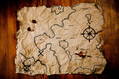 A very old pirate treasure map with hand drawn compass and skull.