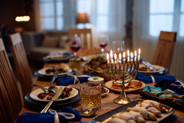 istock Menorah with lit candles on dining table during Hanukkah celebration. 1727530419