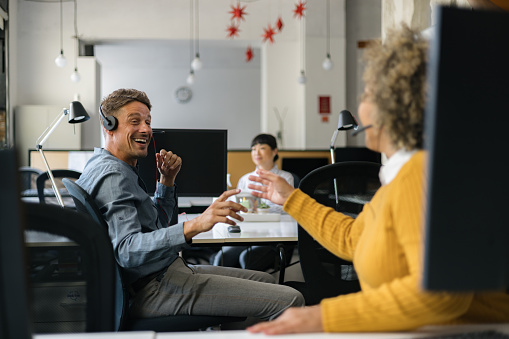 Happy customer service representatives communicating while working on computers in a call center.