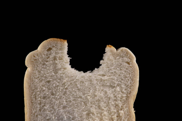 Slice of white bread with bite taken out isolated on a black background