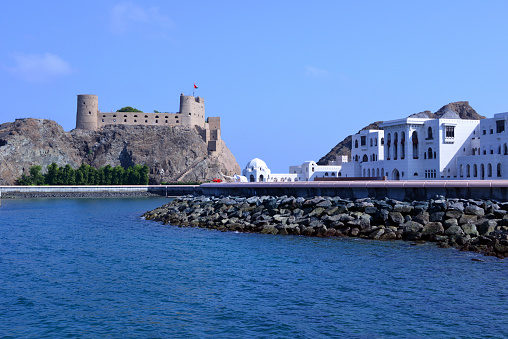 Old Muscat, Oman: Aljalali Fort or Eastern Fort, originally 'Forte de São João' (Fort St. John) - coastal fort in Old Muscat, built by the Portuguese between 1586 and 1588, to protect the port after Muscat had been sacked twice by Ottoman forces. On the right side the white buildings of the Sultan's palace (Al Alam), with bofors coastal artillery guns protecting the waterfront (one covered by a white tarp).
