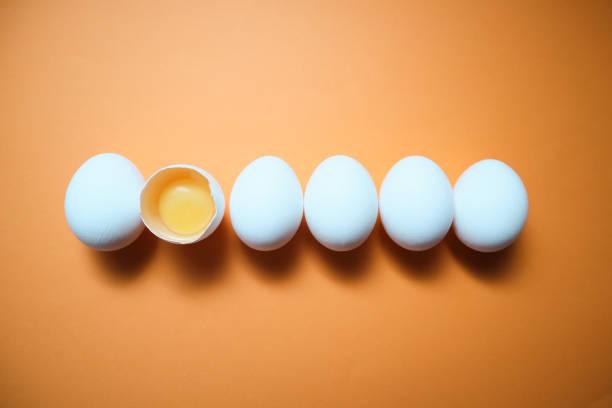 istock Row White eggs and egg yolk on the yellow background. 1727548424