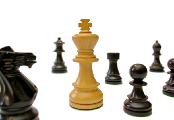 White king surrounded by black chess pieces stock photo