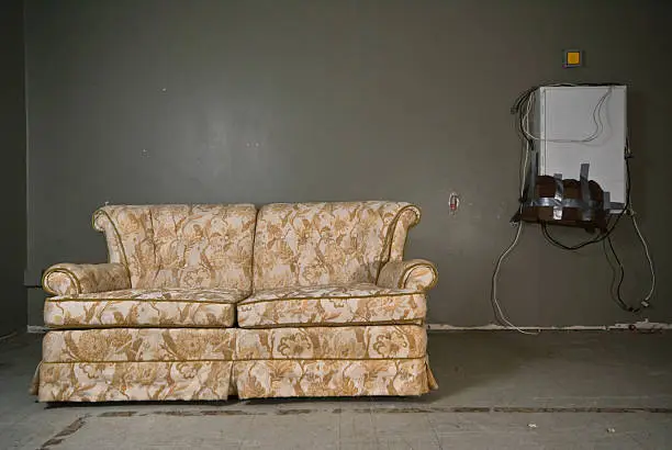 An old and tacky love seat sits in a rundown building.