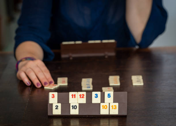 人気のボードゲーム、木製のテーブルの上のルミクブタイルをプレイする2人のプレーヤー - rummy leisure games number color image ストックフォトと画像
