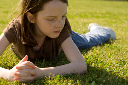 Little girl relaxing in the grass outside