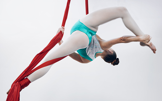 Gymnastics, woman acrobat with performance and muscle, sports and art with athlete on white background. Gymnast, sports and exercise with creativity, talent with fabric and competition in studio