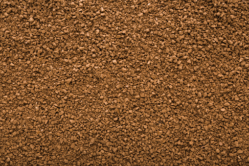 Dry brown granules of instant coffee background. Closeup. Empty place for text. Top down view.