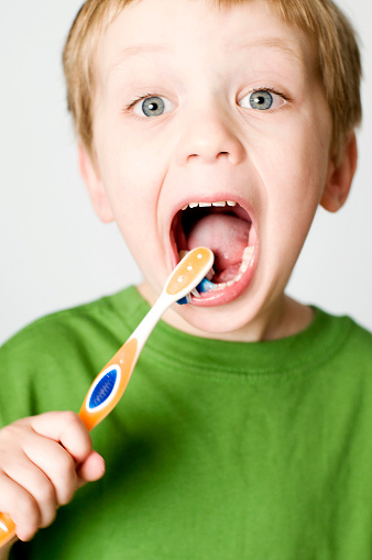 Little boy excitedly brushing his teeth.  VERY selective focus on eyes for dramatic effect.  Very shallow depth of field for dramatic/artistic purposes.